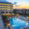Hotel illuminato al tramonto con piscina e lettini.