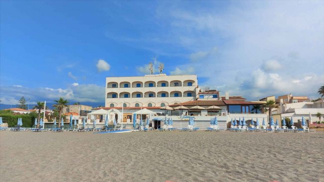 Hotel fronte mare con spiaggia e lettini blu.