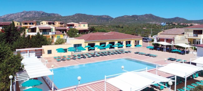 Ampia piscina con lettini e ombrelloni in un resort tra le colline.