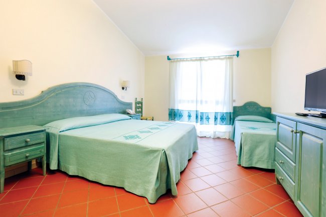 Stanza d'albergo con letto matrimoniale e singolo, mobili in legno verde.