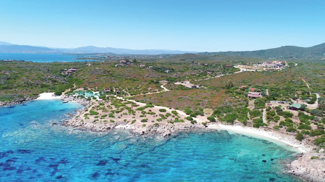 Vista aerea di una costa rocciosa con mare turchese e spiagge.