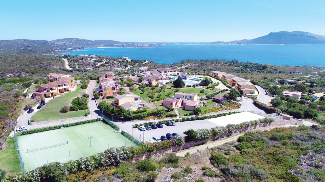 Complesso residenziale vicino al mare con campi da tennis e giardini.