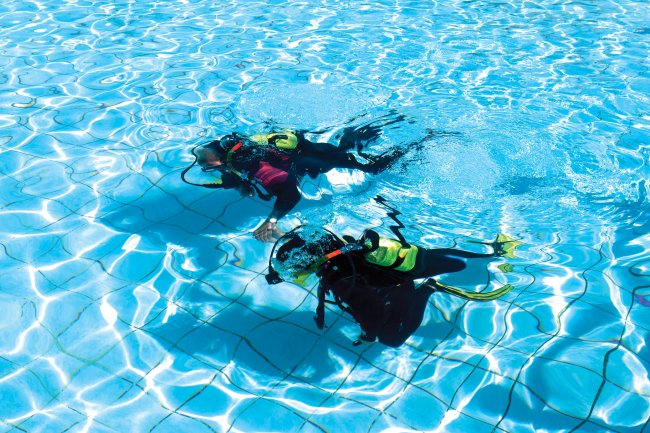 Due subacquei in una piscina limpida.