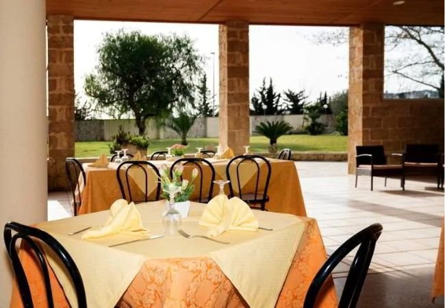 Tavoli apparecchiati in un ristorante all'aperto con vista sul giardino.