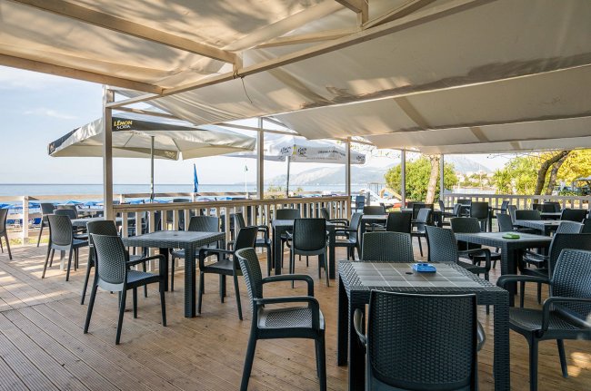 Terrazza con tavoli e sedie sotto tende beige.