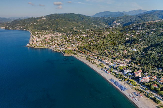Veduta aerea di una costa con spiaggia e colline.