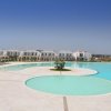 Ampia piscina dal design moderno con edifici bianchi sullo sfondo e cielo sereno.