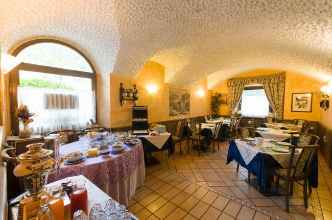 Sala da pranzo con soffitto ad arco e tavoli apparecchiati.