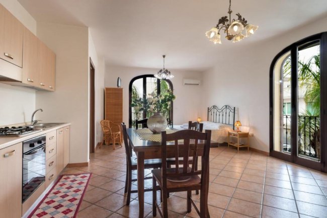 Cucina e zona pranzo con letto e ampie finestre.