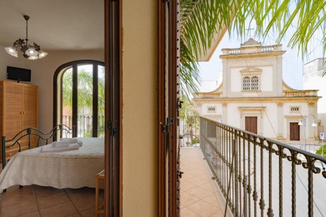Vista sul balcone con palme e edificio.