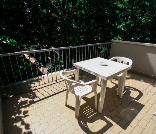 Balcone con tavolo e sedie in plastica bianca.