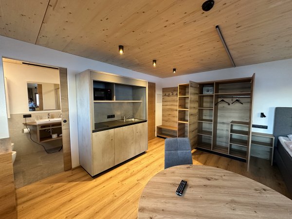 Stanza con armadio, tavolo e vista su un bagno.