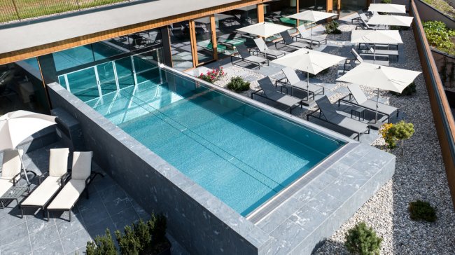 Piscina esterna con lettini e ombrelloni.