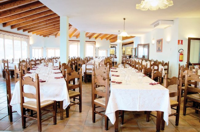Ampia sala da pranzo con tavoli apparecchiati.