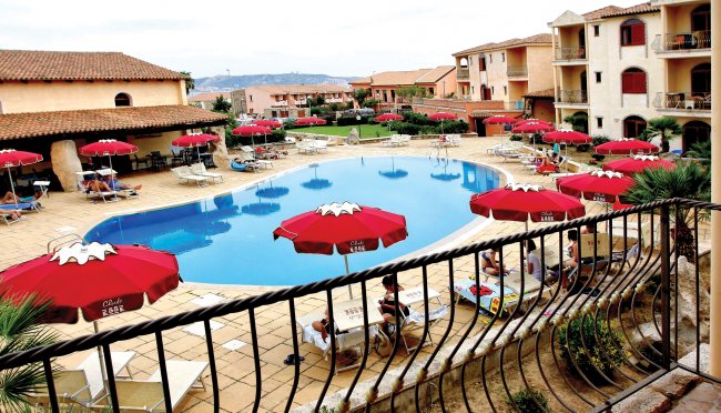 Piscina all'aperto circondata da sedie a sdraio e ombrelloni rossi.