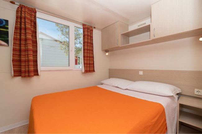 Camera con letto matrimoniale e copriletto arancione.