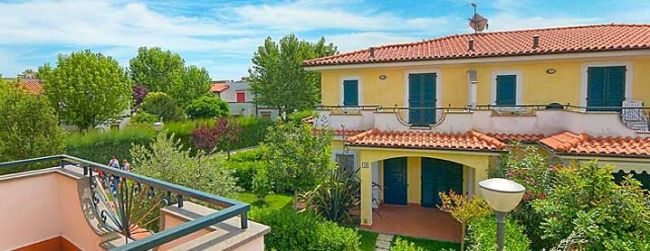 Casa gialla con tetto rosso e giardino.