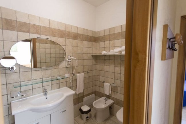 Bagno con specchio ovale e piastrelle beige.