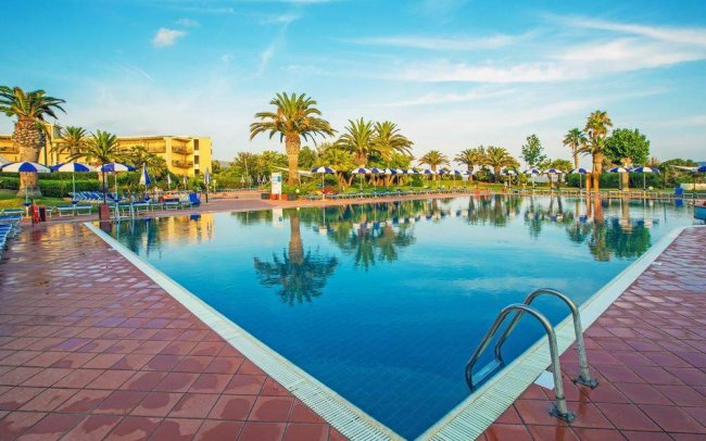 Piscina con lettini e palme attorno.