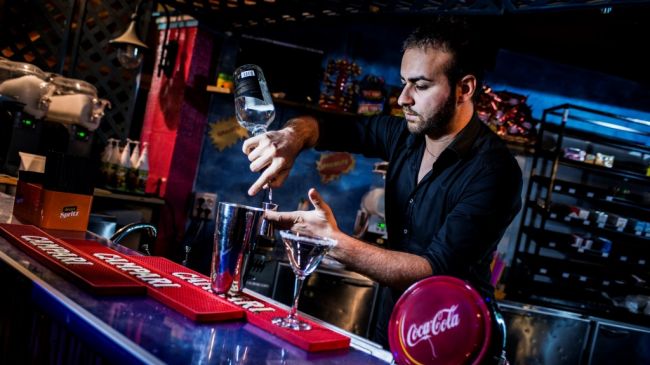 Bartender che prepara un cocktail al bancone.