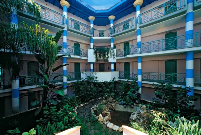 Cortile interno con balconi e vegetazione lussureggiante.