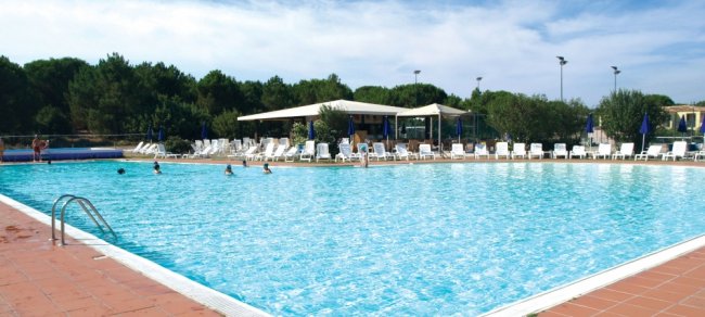 Grande piscina all'aperto con sedie a sdraio e ombrelloni.