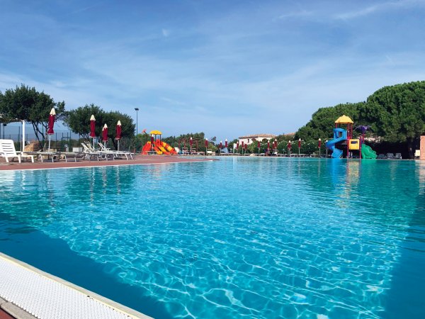 Piscina con scivoli e ombrelloni rossi.