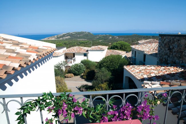 Vista mare e case dal balcone fiorito.