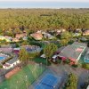 Vista aerea di un centro sportivo con campi da tennis e piscina, immerso nel verde.
