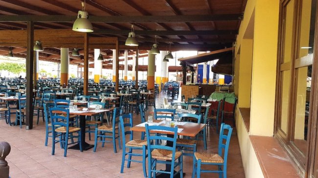 Ristorante all'aperto con tavoli e sedie blu.