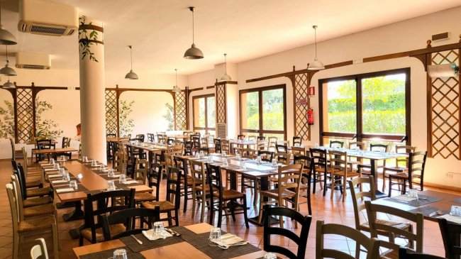 Sala da pranzo con tavoli e sedie ordinate.